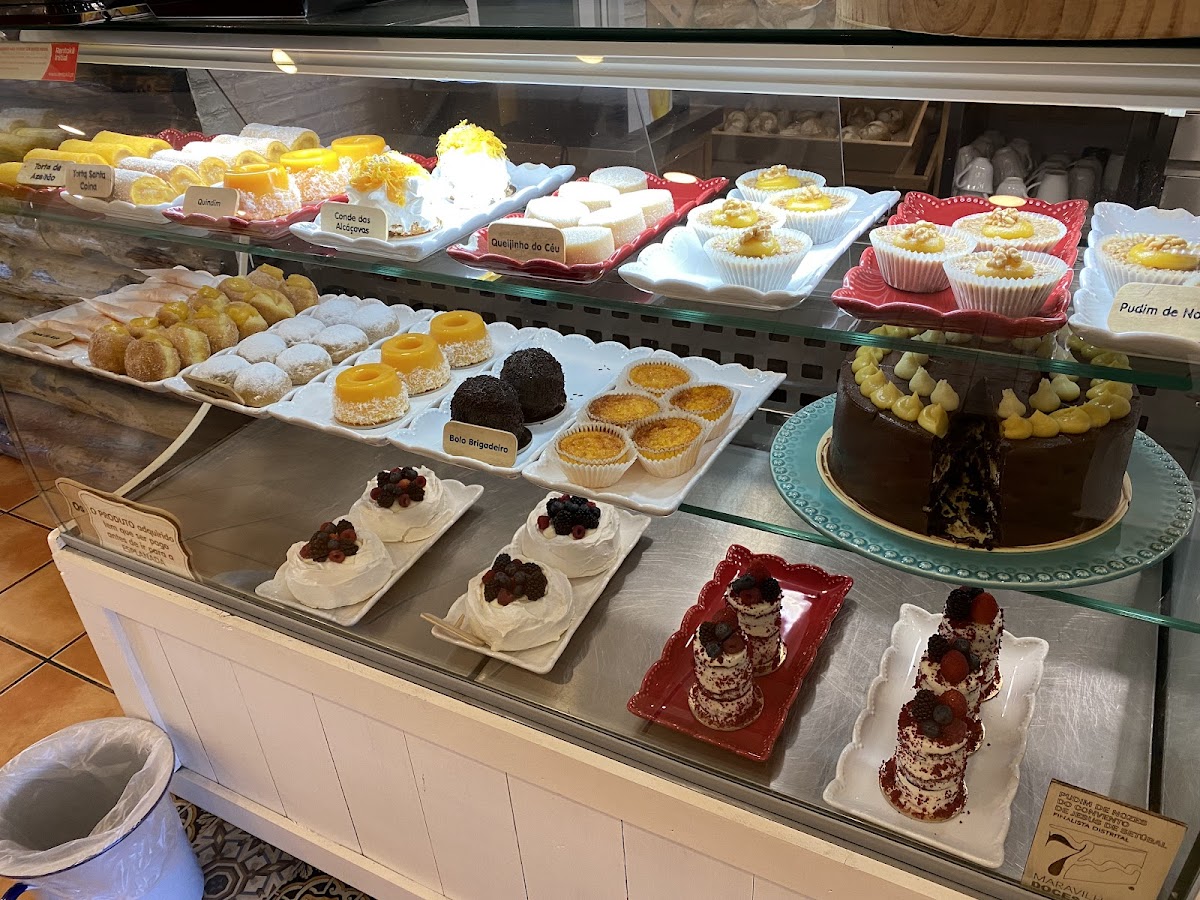 Expositor da confeitaria com queijinhos do céu, pavlovas com frutos vermelhos, tartes e bolos de autor.