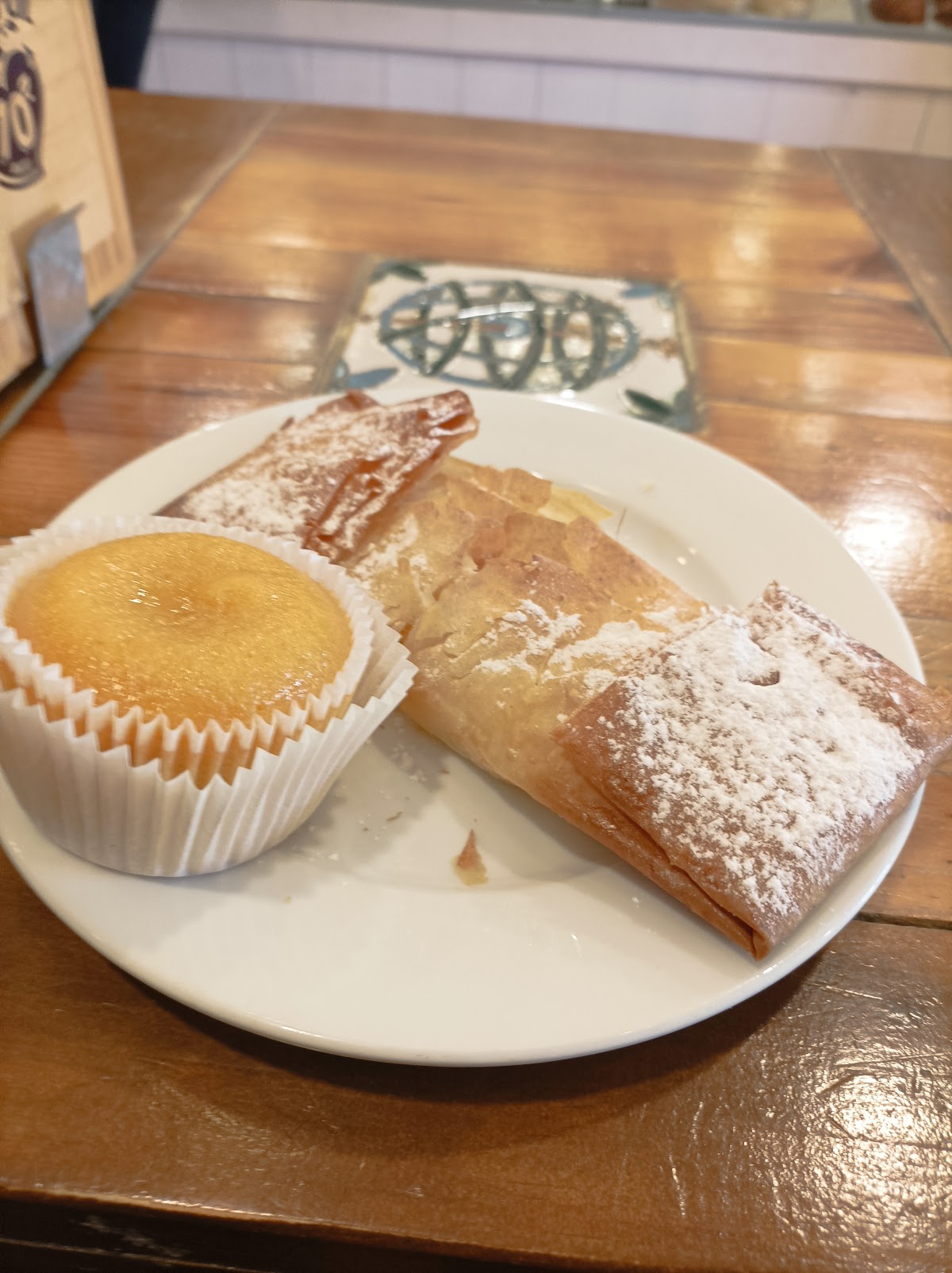 Prato com uma coininha e um travesseiro polvilhado de açúcar, na mesa de madeira da casa.